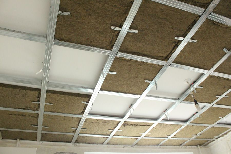 An image of a false ceiling structure with a grid, tracks, and metal panels.