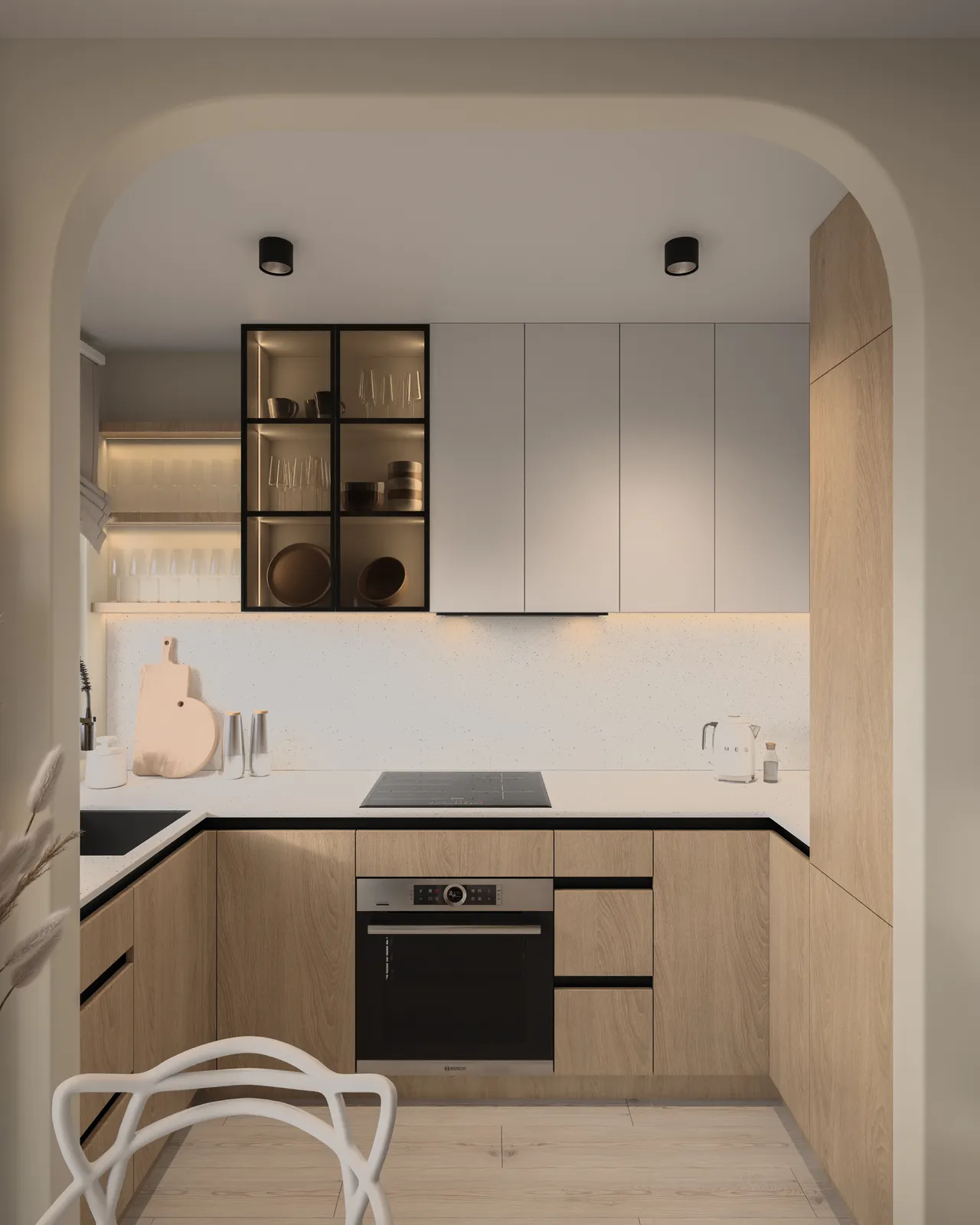 A modern kitchen featuring sleek cabinetry in light wood and gray, with black accents. The cooktop is centrally located, and there's a minimalist design with open shelving displaying glassware. Natural light illuminates the space through an archway.