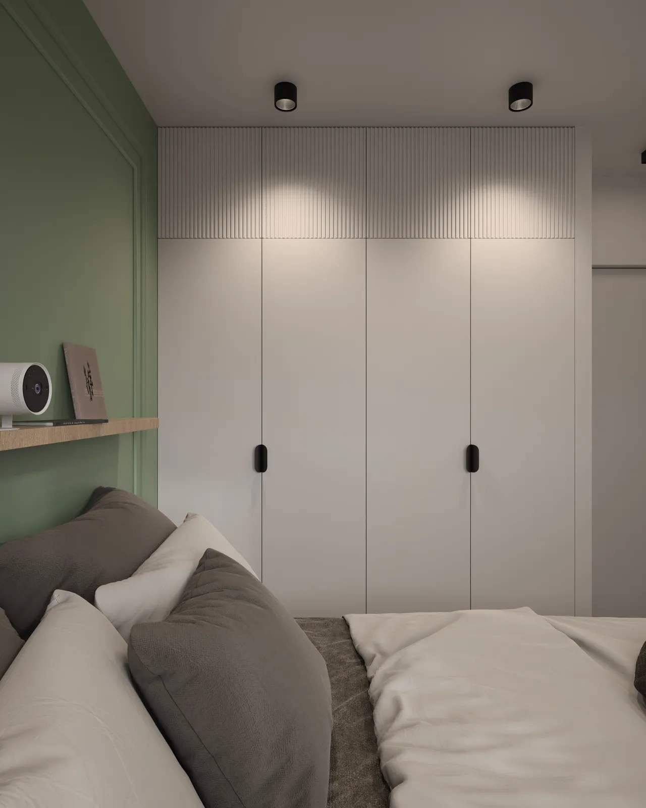 A modern bedroom design featuring a bed with gray and white bedding, a green accent wall, and a sleek wardrobe with vertical paneling. The room is well-lit with recessed lighting.