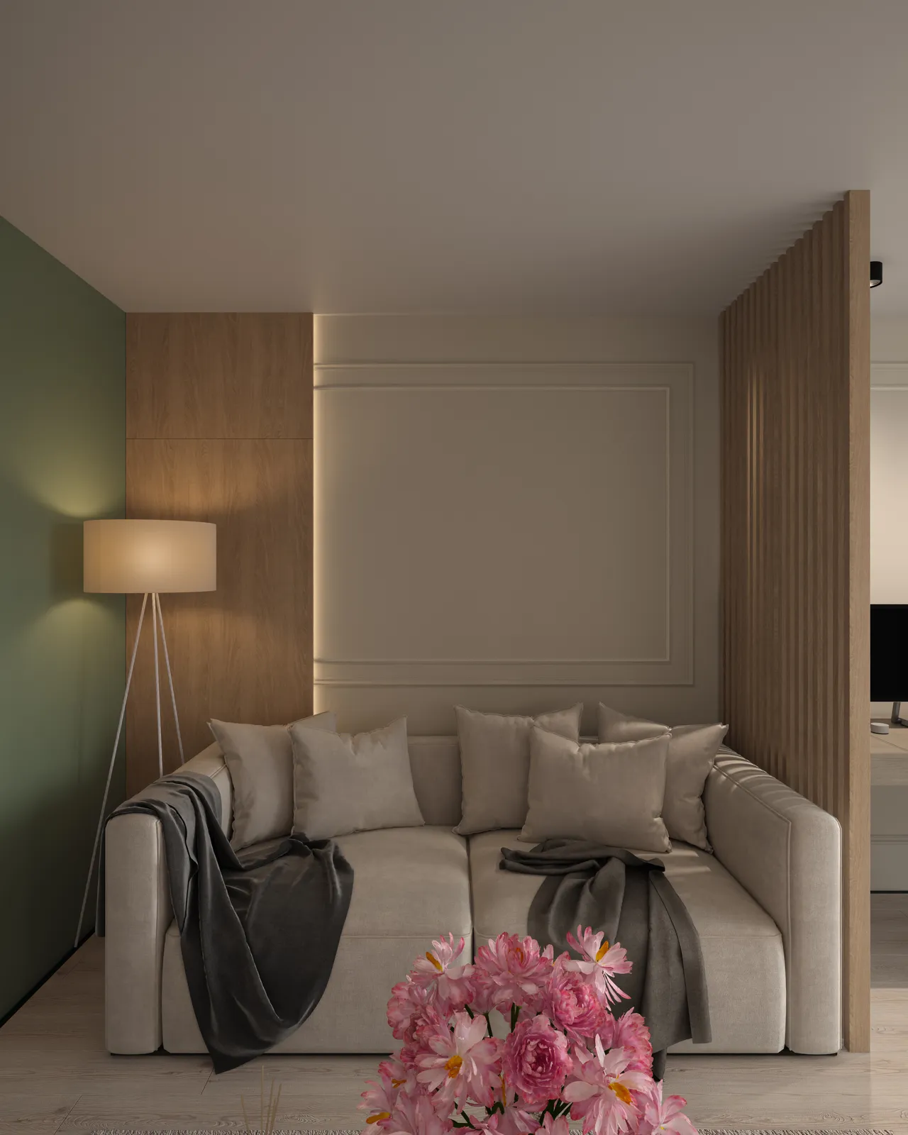 A cozy living room featuring a white sofa with several cushions, a gray throw blanket draped over one side, soft lighting from a floor lamp, and a decorative arrangement of pink flowers in the foreground.