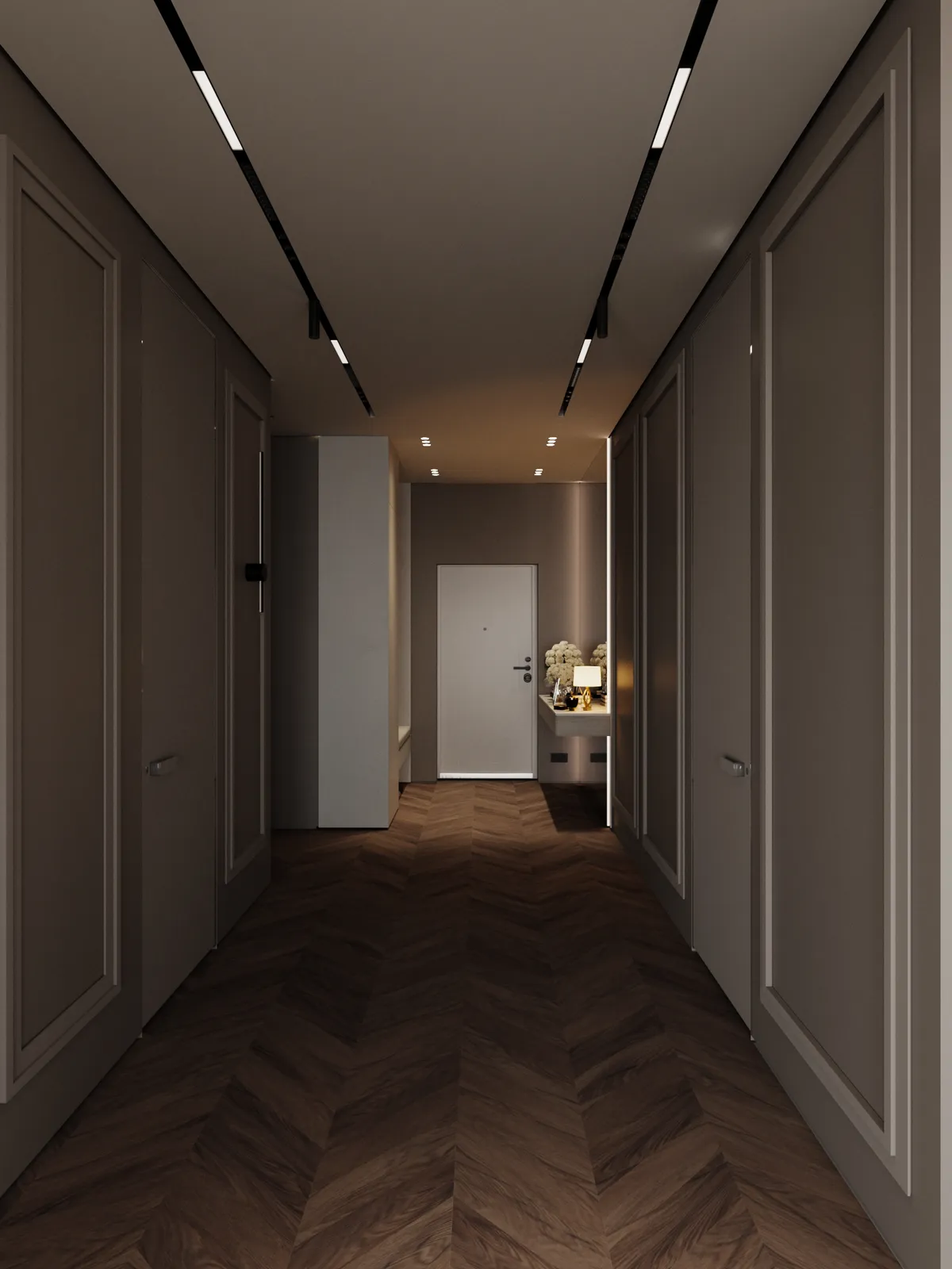 A modern hallway with dark herringbone wood floors, beige paneled walls, recessed ceiling lights, and a closed door at the end with a small console table and decorative items beside it.