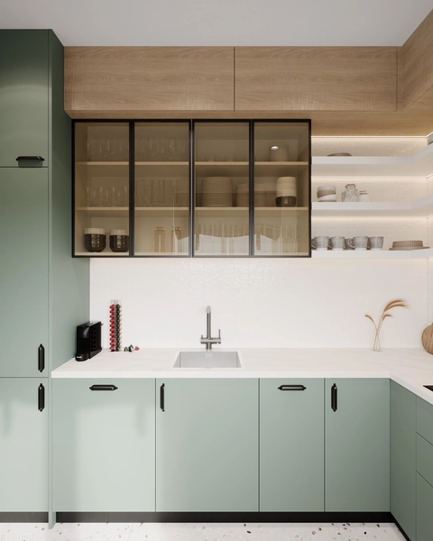 Modern kitchen with pale green cabinets, open shelves holding dishes, glass-front cabinets with glassware, white backsplash, and a sink under a wooden cabinet.