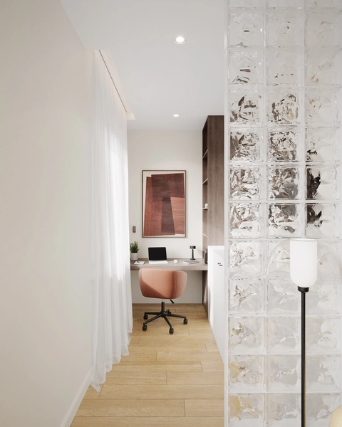 A minimalist home office with light wood floors, a glass block wall, and sheer white curtains. A small desk with a pink chair is adorned with a plant, lamp, and abstract art, creating a calm and modern feel.
