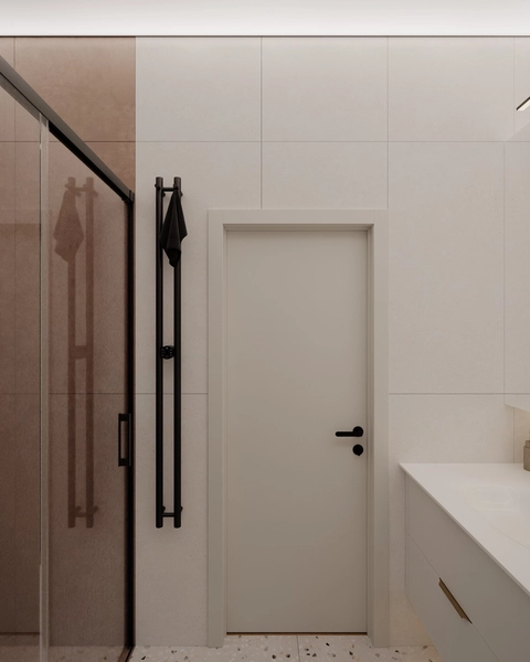 A modern bathroom featuring a glass shower, a white door, and minimalist decor.