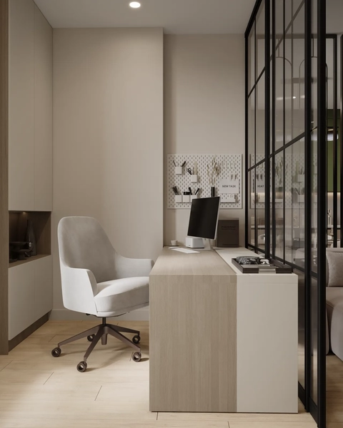 A modern office space featuring a sleek desk, an ergonomic white chair on wheels, and a computer monitor. The room has light-colored walls and wooden flooring, with a glass partition separating the workspace from another area.