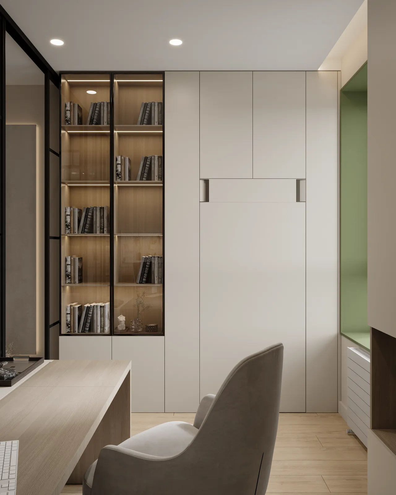 A modern, minimalistic office space featuring a light-colored desk and a comfortable chair. There is a built-in bookshelf with glass doors displaying neatly arranged books, alongside a sleek cabinet in the wall. The walls are painted in neutral tones with one green accent wall.
