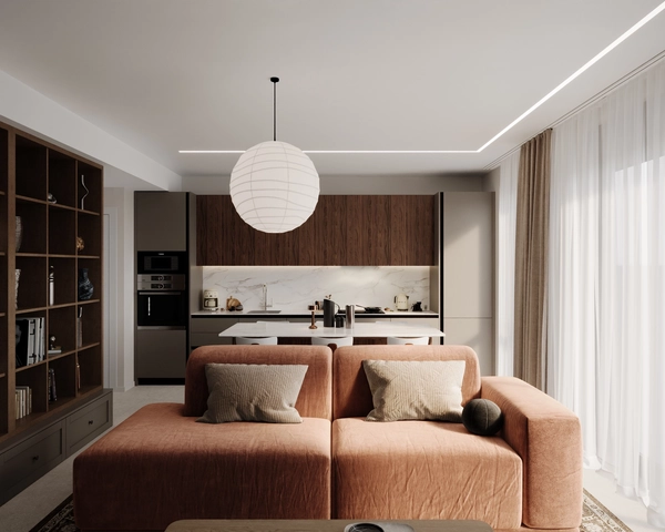 The open-plan living area, with a modular sofa in terracotta velvet, a spherical paper pendant lamp, a wooden bookcase and a kitchen with dark wood fronts and a white marble countertop.