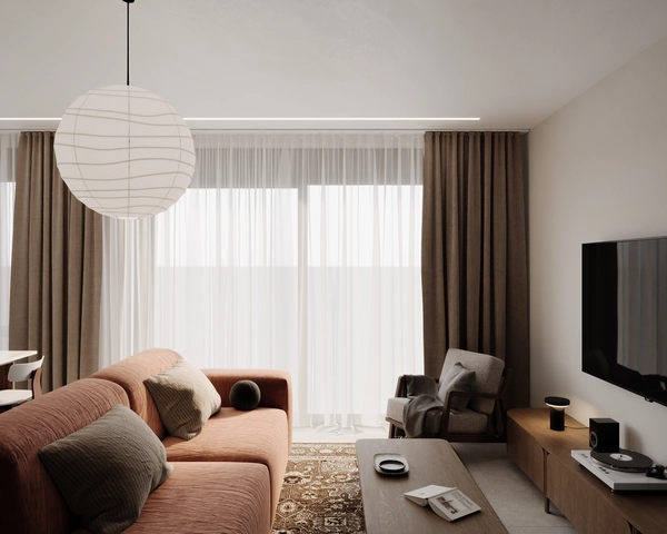 The living room lit naturally through the large window with sheer curtains and beige drapes, a terracotta modular sofa, a wooden armchair with grey upholstery, a rug with an oriental pattern and a wall-mounted television.