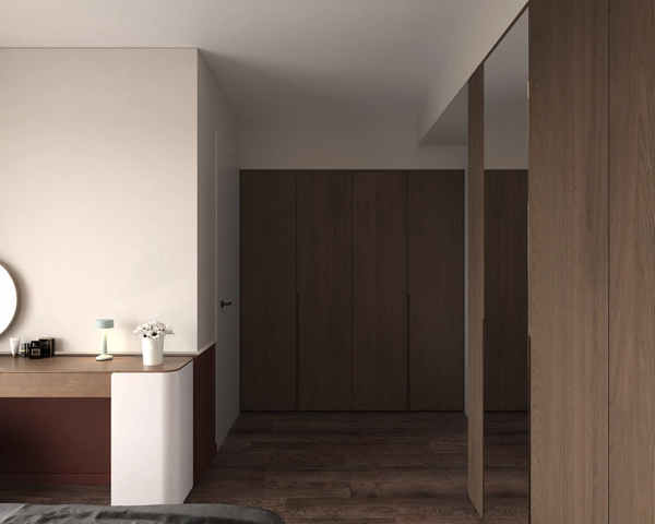 The dressing area of the bedroom, with a light wood countertop, a terracotta panel, a white storage unit and tall dark wood wardrobes on the opposite wall.