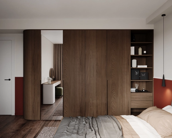 The master bedroom with a tall walnut wardrobe, a mirror panel reflecting the dressing area, open shelves with decor and the bed with grey linen in the foreground.