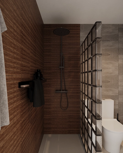 A shower cabin with a dark fluted wood panel, a black rain shower fitting, a black wall-mounted shelf and a partition of glass blocks.