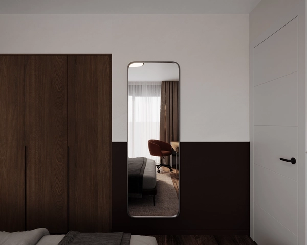 The second bedroom, with a tall mirror with a rounded frame, a dark wood wardrobe, a chocolate-toned lower wall and a white door with a black handle.
