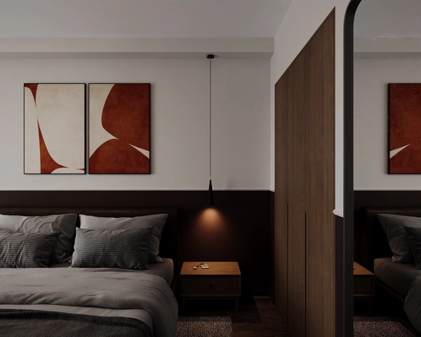 A bedroom with a double bed, grey linen, two abstract artworks in brick tones, a cone pendant lamp above the wooden nightstand and a tall wardrobe reflected in the mirror.