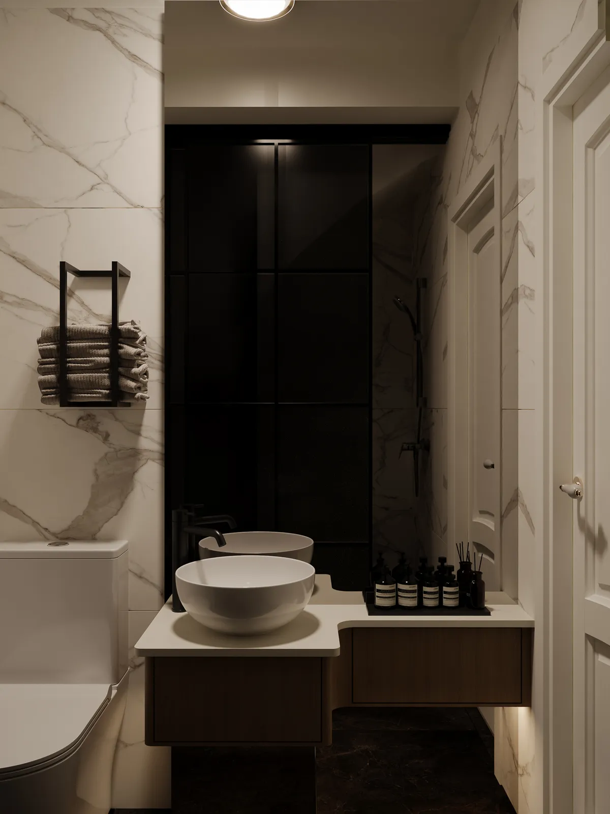 A modern bathroom featuring marble walls, a white sink on a wooden countertop, and dark cabinetry. Towels are neatly stacked on a rack, and there are various toiletries displayed.